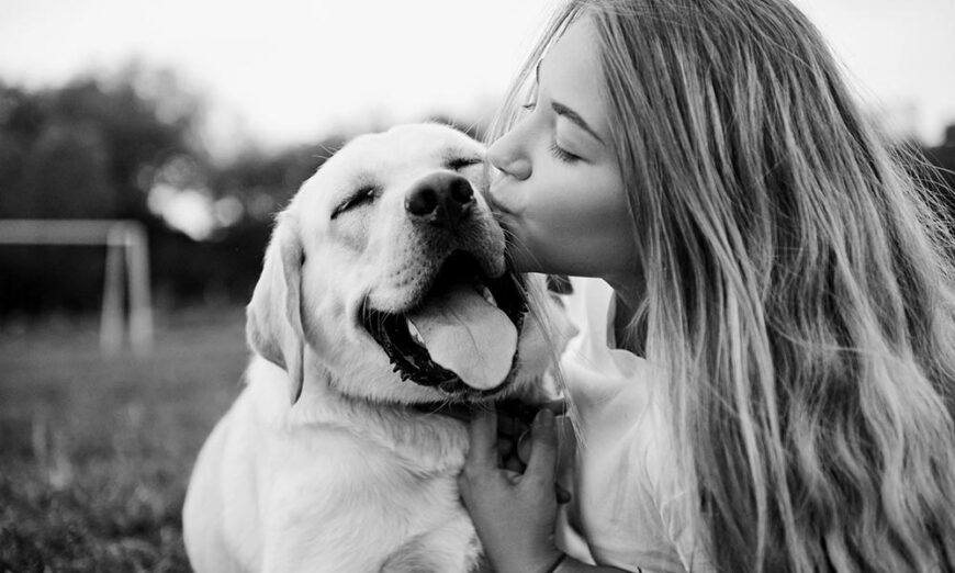 Girl kissing her dog outside backyard black and white photo