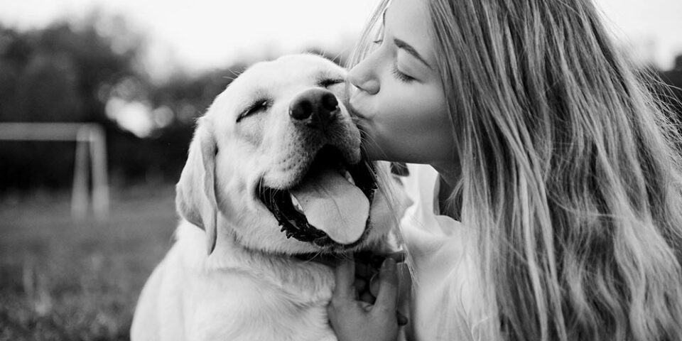 Girl kissing her dog outside backyard black and white photo