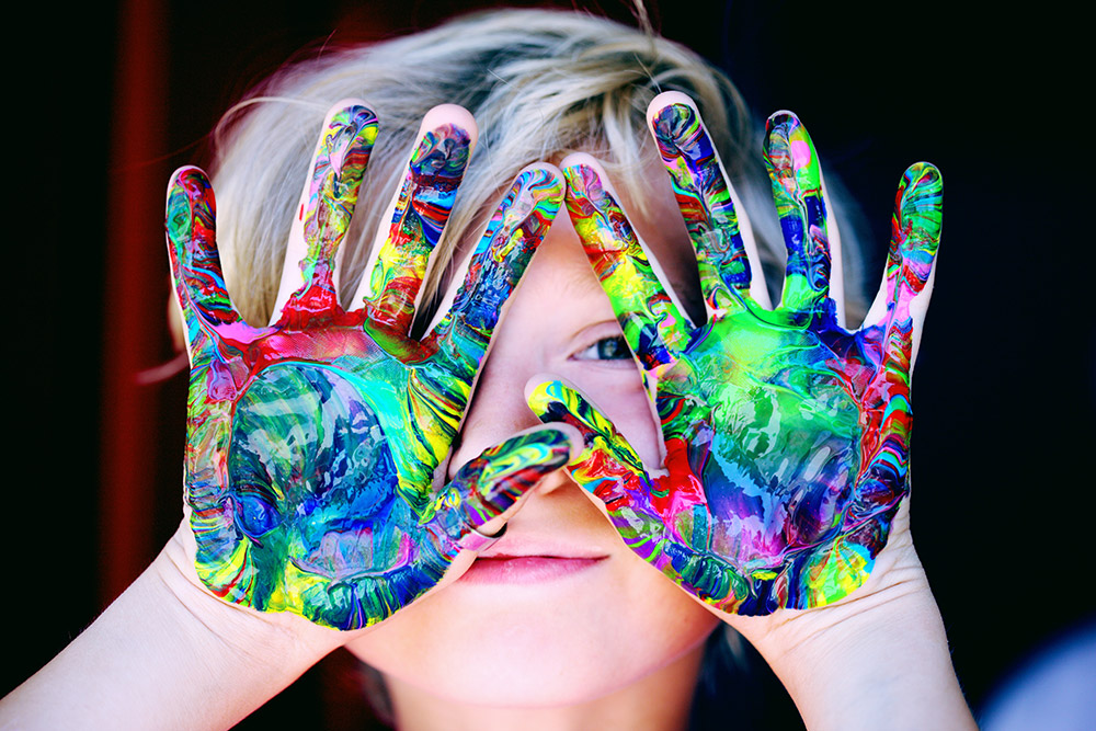 Little boy with colourful paint on his hands