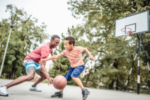 Dad and son playing basketball in their yard
