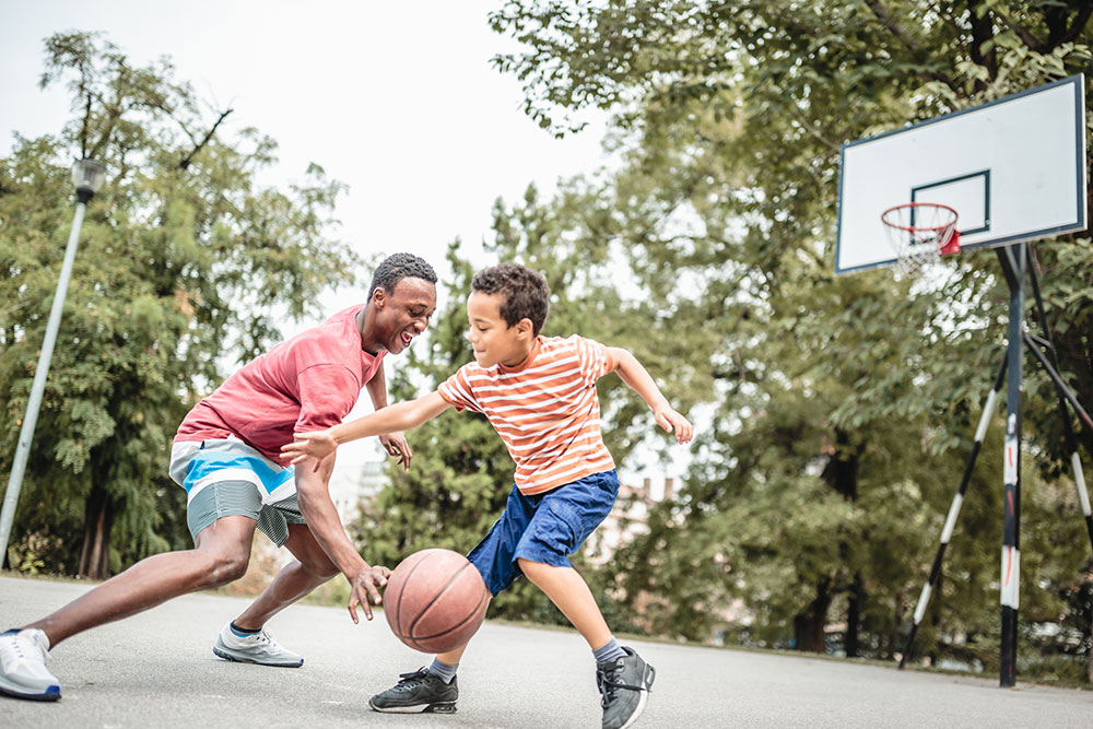 Dad and son playing basketball in their yard