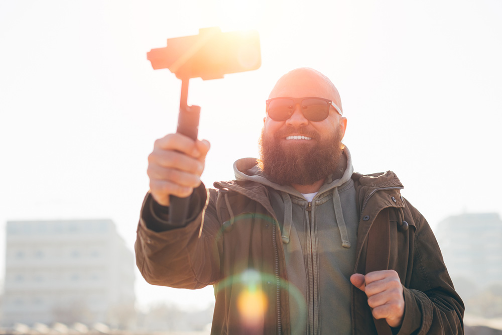 Man holding a gimbal with a smartphone filming a vlog