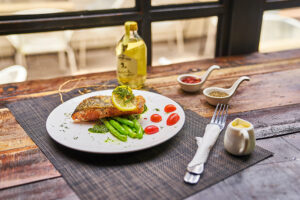 Wooden table with plate of salmon and sides