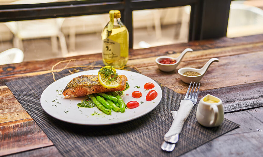 Wooden table with plate of salmon and sides