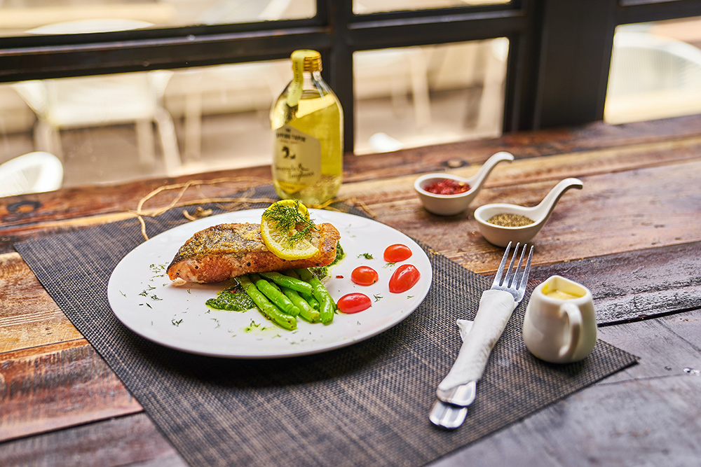 Wooden table with plate of salmon and sides