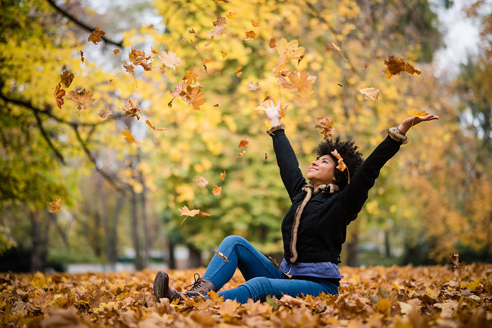 Lady sitting on the ground catching leaves